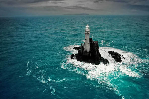 Lighthouse standing on a rock in open sea
