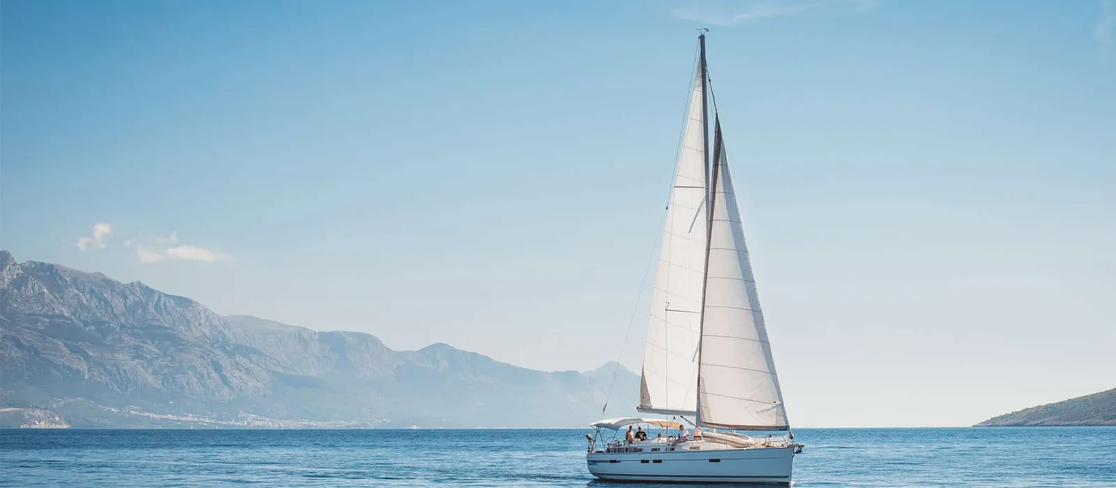 Sailboat under full sail with mountains behind