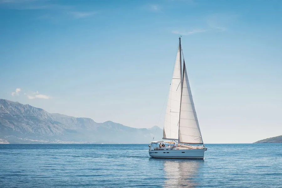 Sailboat under full sail with mountains behind