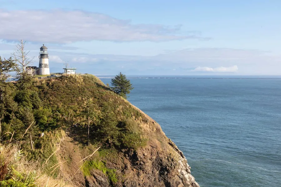 Lighthouse on a wooded headland above the ocean