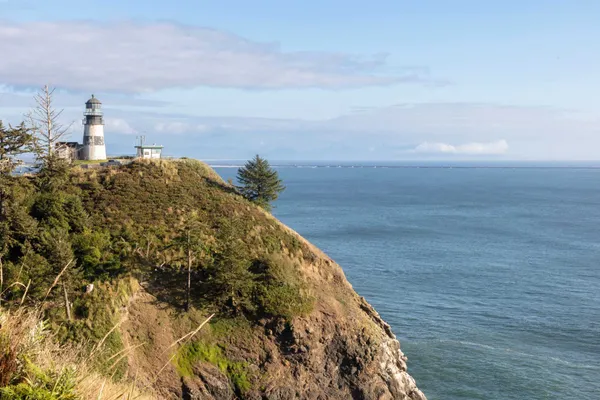 Lighthouse on a wooded headland above the ocean