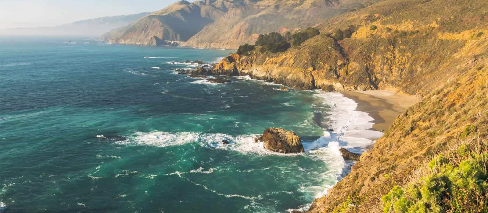 Turquoise cove below coastal hills
