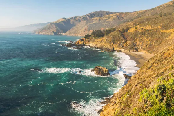 Turquoise cove below coastal hills