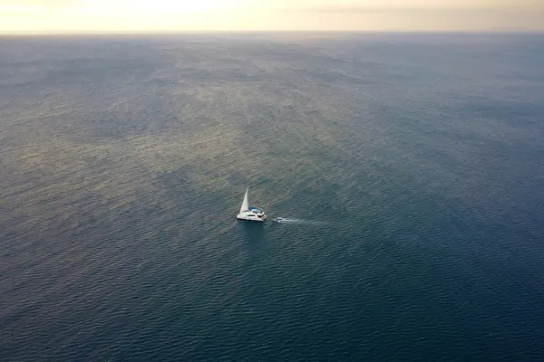 Lone sailboat on open water, seen from above