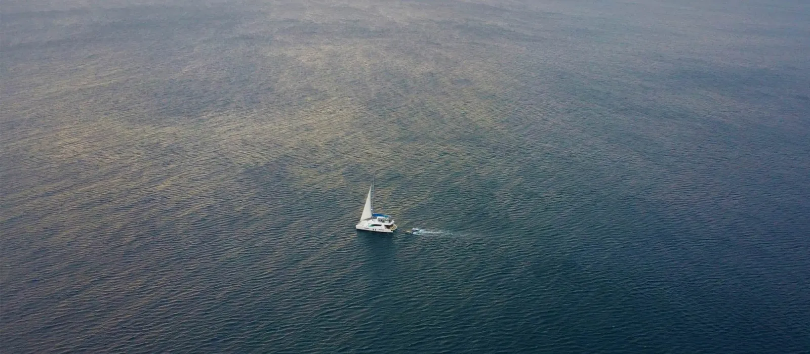 Lone sailboat on open water, seen from above