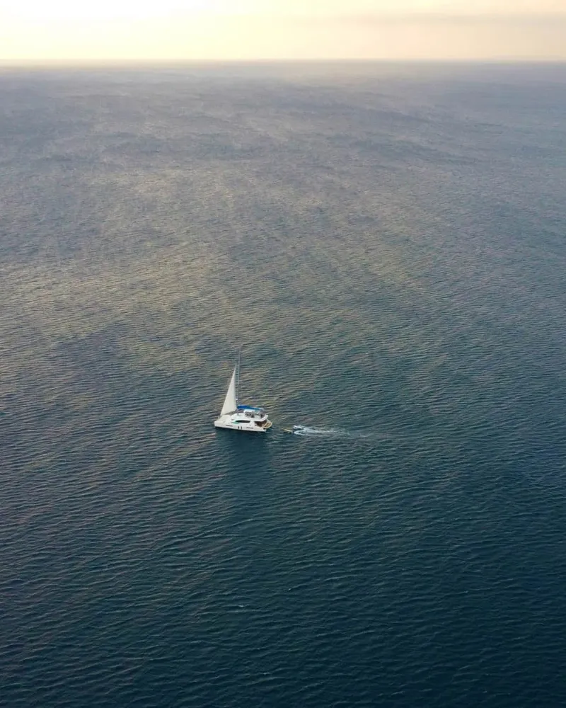 Lone sailboat on open water, seen from above
