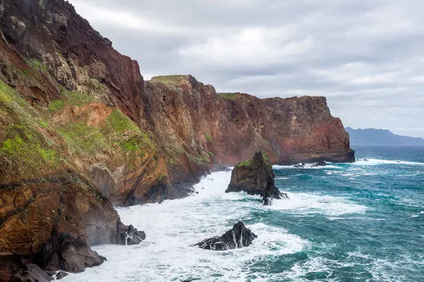 Waves breaking against red sea cliffs