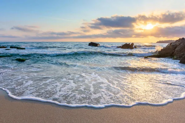 Waves washing onto a beach at sunset